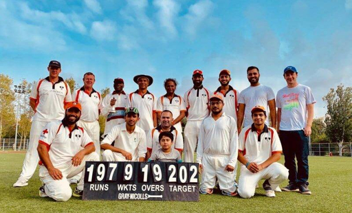 Cricket team group photo beside the scoreboard